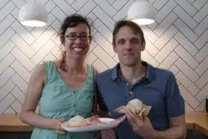 A couple smiles while standing in front of a tiled wall on an Off the Beaten Path Food Tour in Harvard Square.