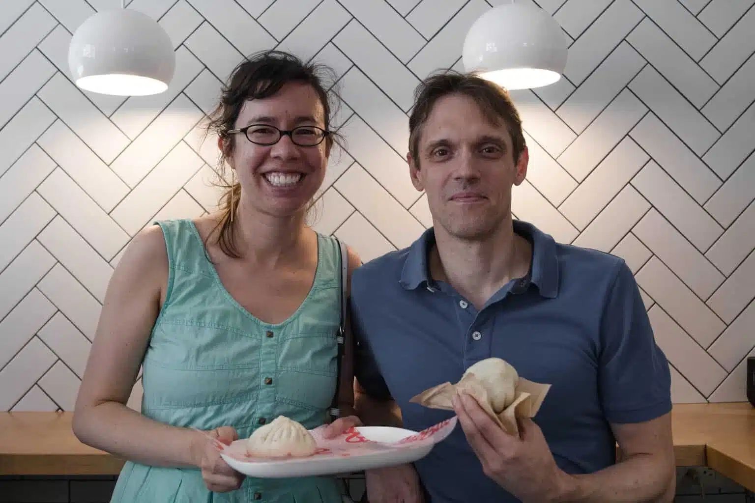 A couple smiles while standing in front of a tiled wall on an Off the Beaten Path Food Tour in Harvard Square.
