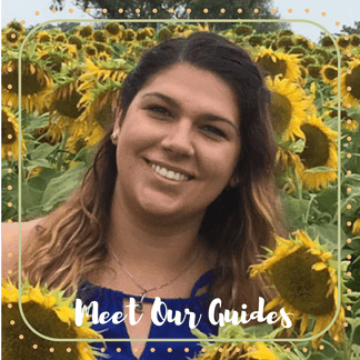 Michelle, an Off the Beaten Path Food Tour guide, stands in a field of sunflowers smiling. 