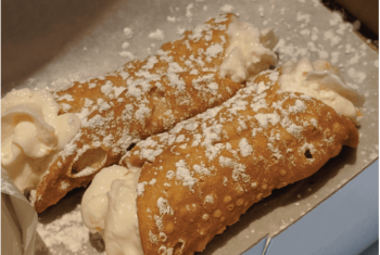 Two delicious cannolis sit in a box as seen on Off the Beaten Path's Roslindale Boston Food Tour.