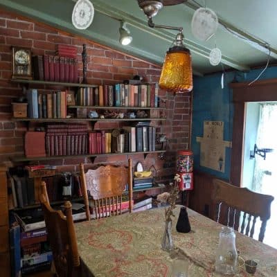 The interior of a cozy cafe with a brick wall with bookshelves and a table with chairs. 
