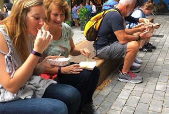 A mother and daughter share a snack while sitting in Bow Market while in Union Square on an Off the Beaten Path Food Tour.